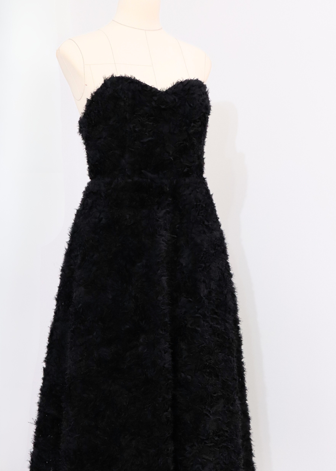 Close-up of body-shaping corset on timeless midi black dress with sweetheart neckline
