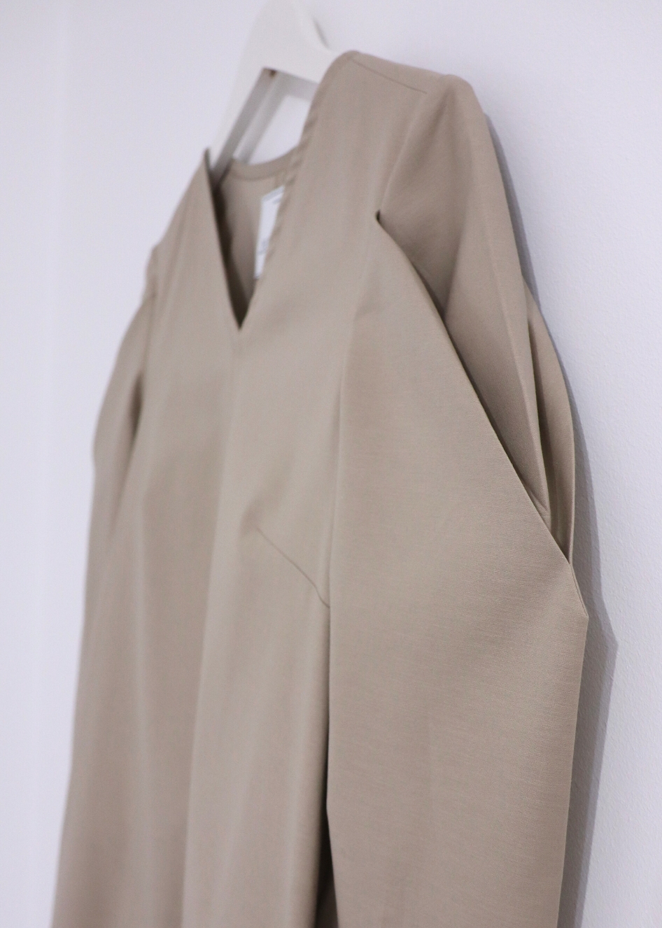 HERET beige cotton fall dress hanging on a hanger, relaxed fit and long sleeves