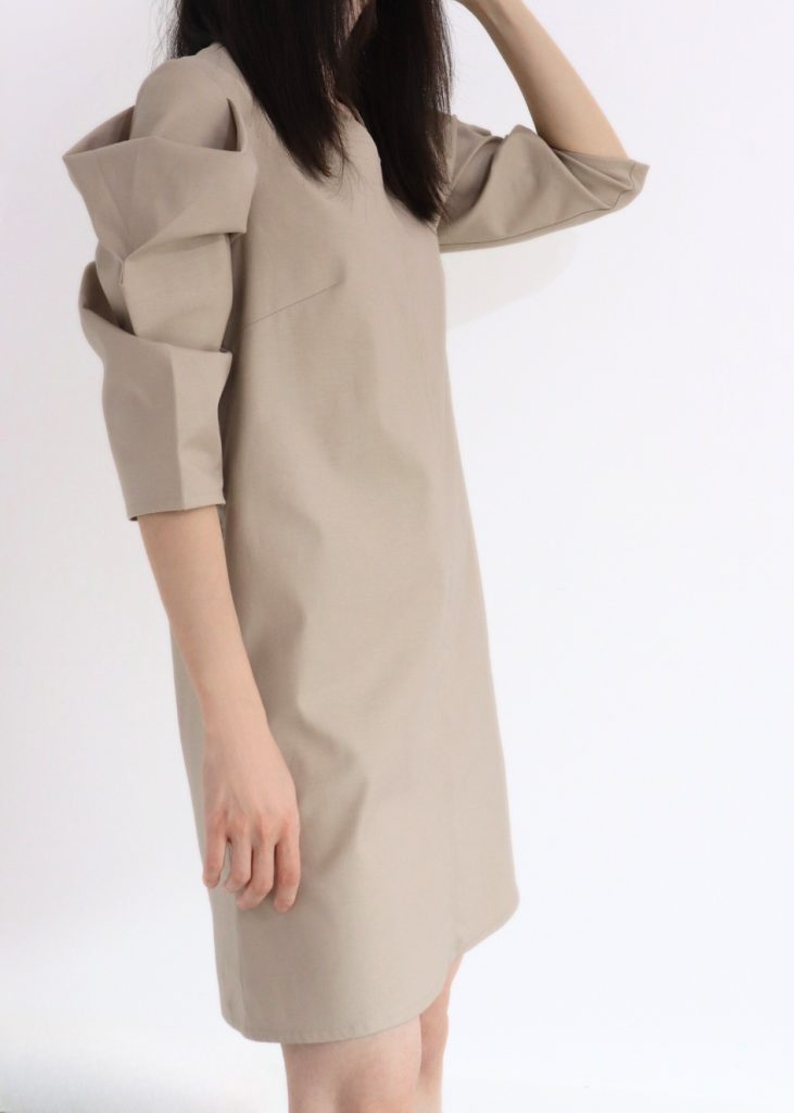 Side view of HERET beige cotton fall dress highlighting shape and length